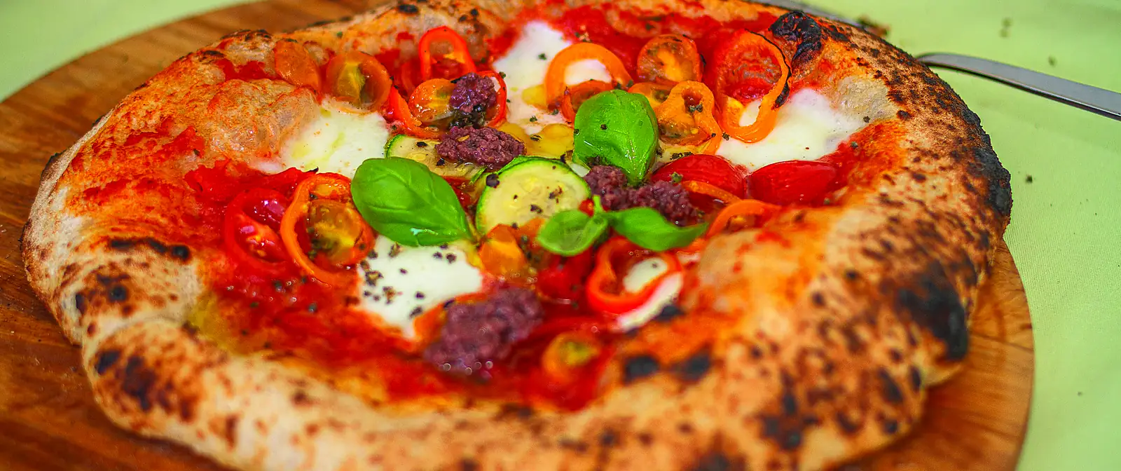 Pizza napolitana inteira, recém-assada, vista de cima sobre uma tábua.